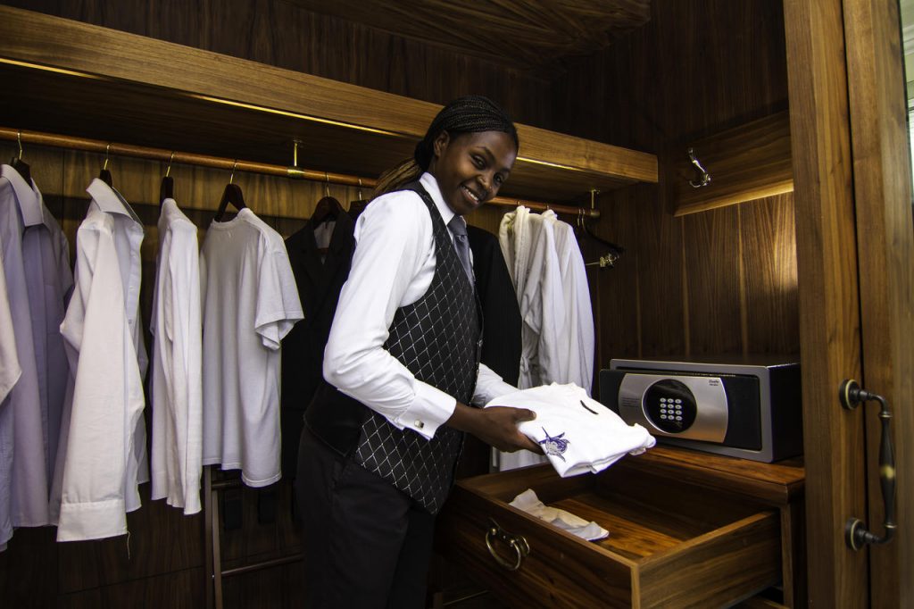 female butler unpacking to the luxury hotel suite wardrobe