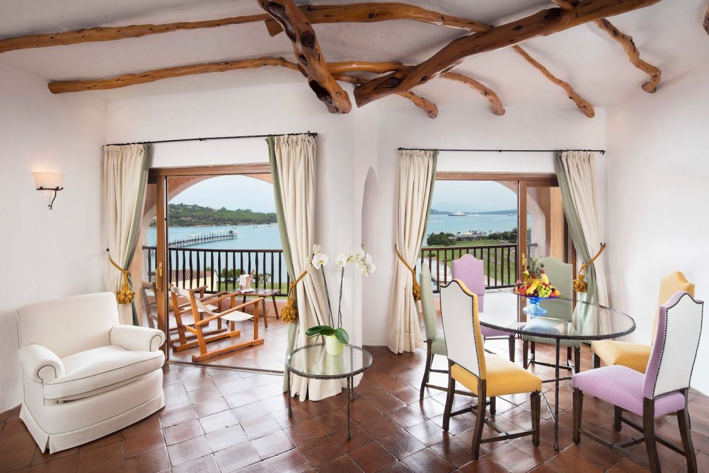 Bright hotel suite interior with colored chairs and sea view