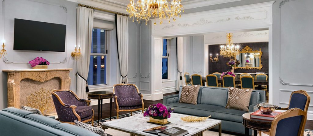 richly decorated royal suite living and dining room with white wooden walls and golden chandeliers