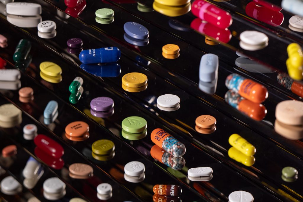 pills and tablets in a black backgrounded cabinet as a art piece designed by Damien Hirst
