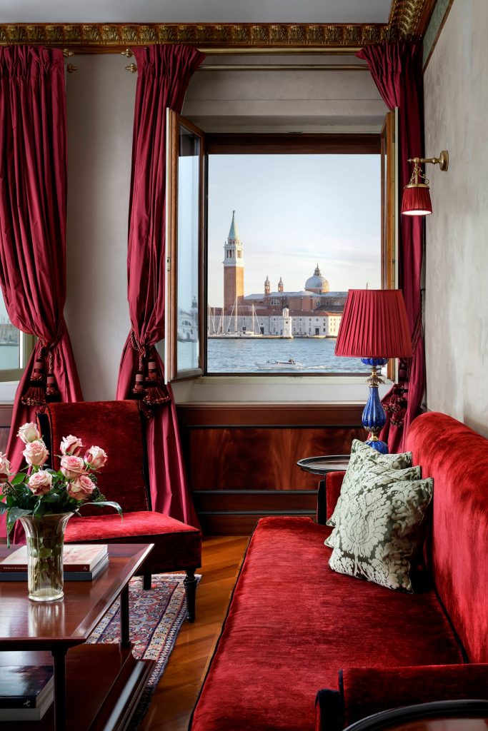 Red sofa and armchair with red luxury curtains and beautiful view to Venice lagoon