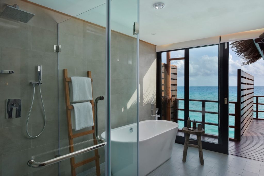 glass shower and bathtub overwater villa bathroom in the maldives
