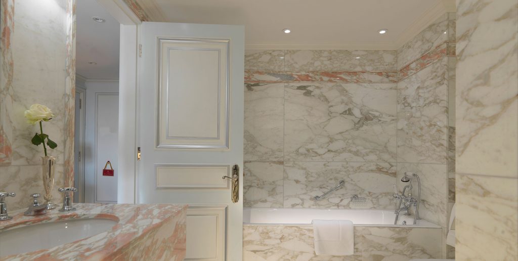 full marble bathroom with white door and bathtub, huge marble boards on the wall