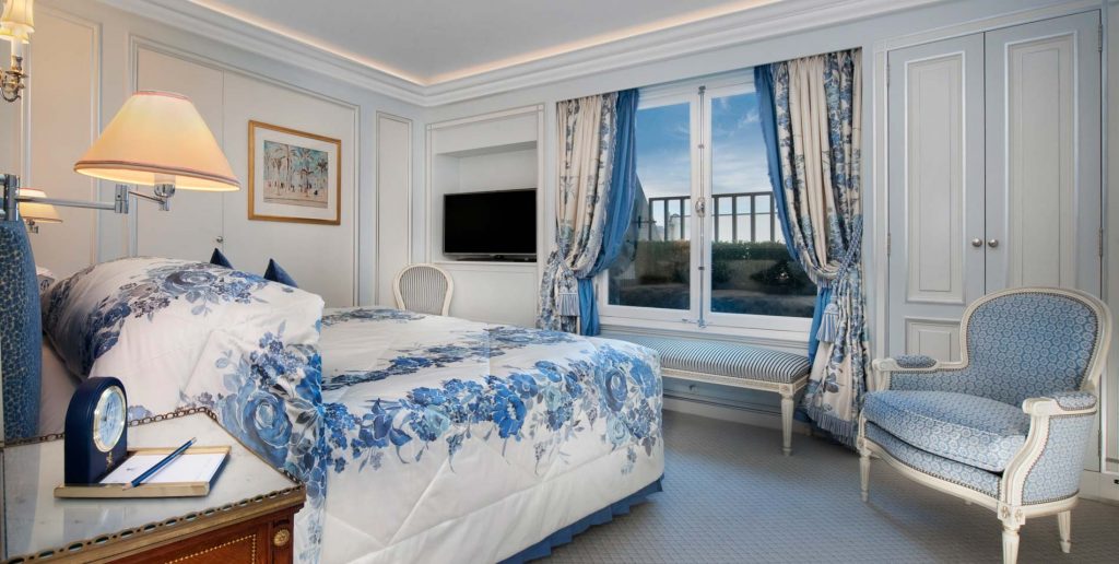 blueish bedroom with beautiful curtains and huge bed and armchair with blue cloth